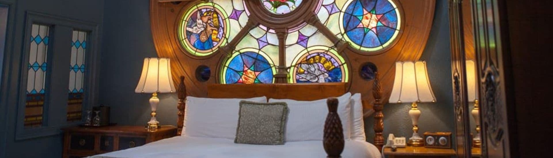 A cozy bedroom featuring a large stained glass window above a neatly made bed.