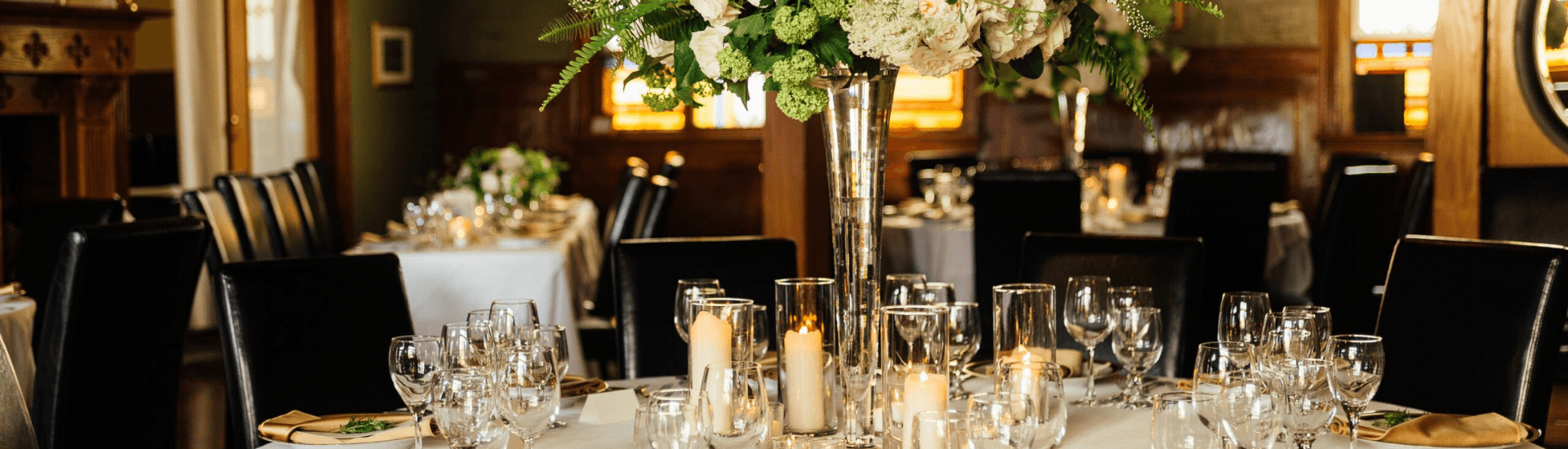 A beautifully set dining table with elegant floral centerpieces and candlelight.