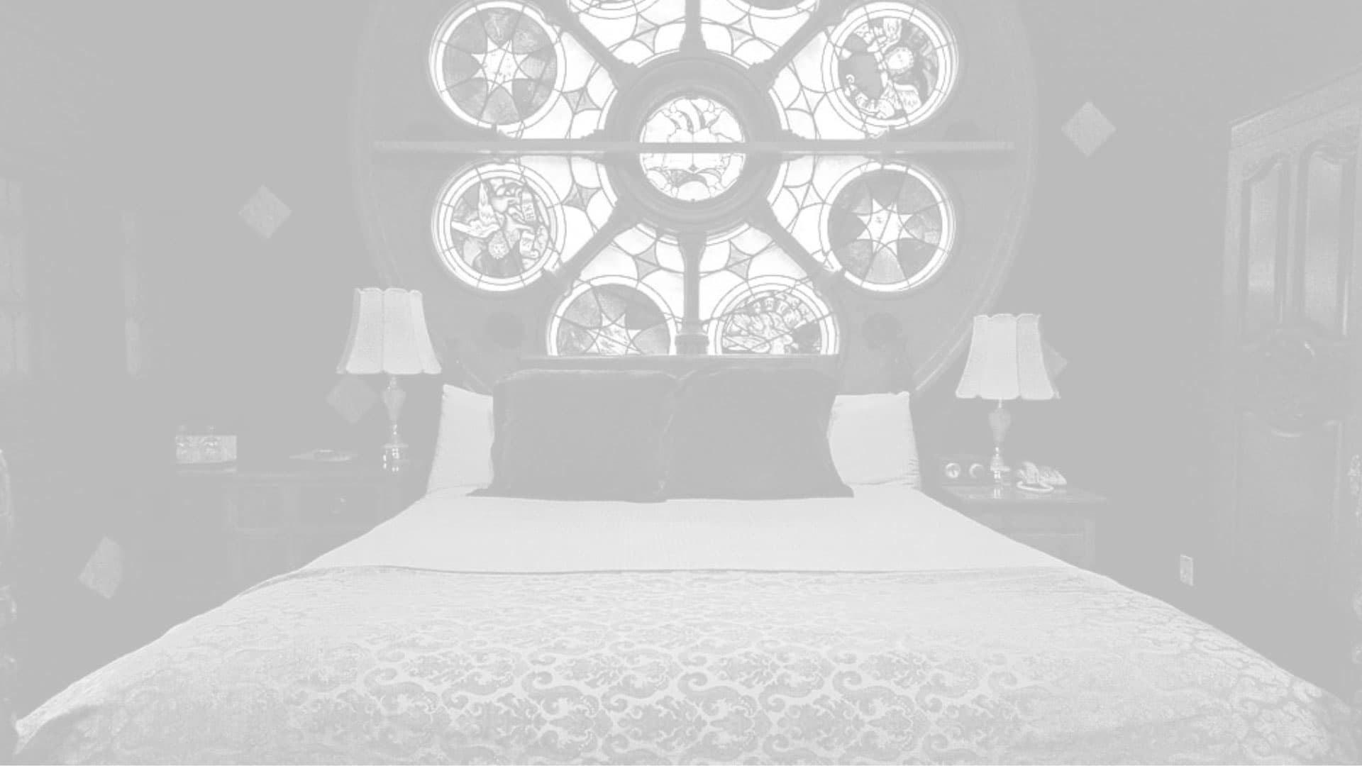 A cozy bedroom with a large stained-glass window and elegant decor.