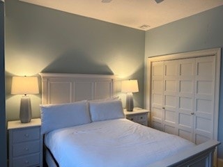 A cozy bedroom featuring a large bed, two bedside lamps, and a closet with a paneled door.