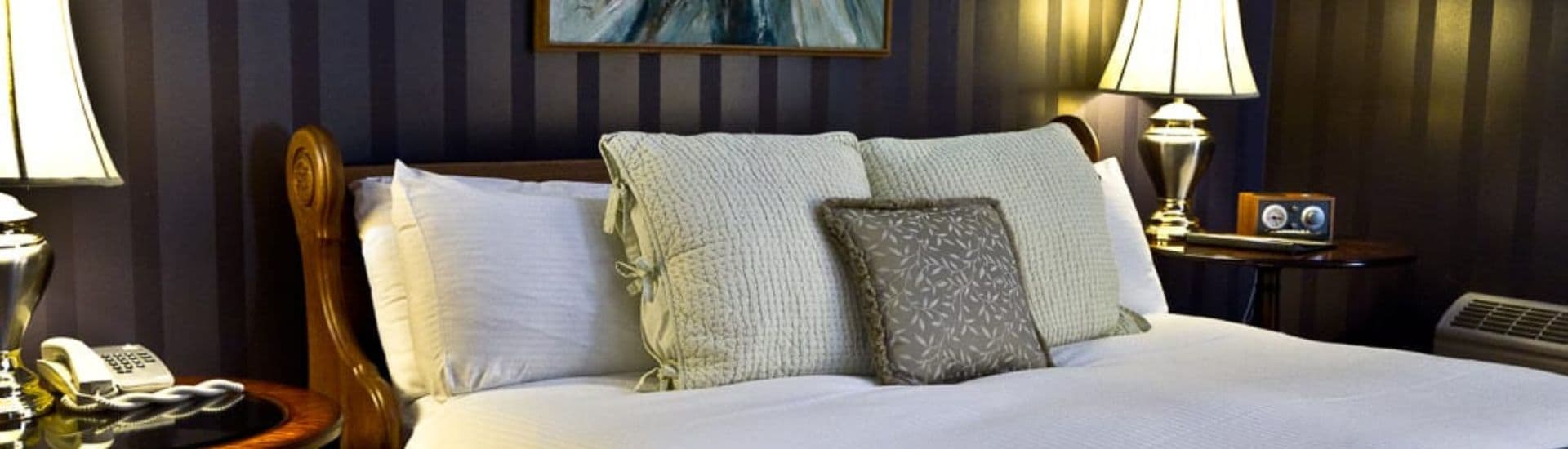 A cozy bedroom featuring a neatly made bed with decorative pillows and bedside lamps.