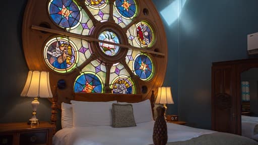 A cozy bedroom featuring a large round stained glass window and elegantly styled furnishings.
