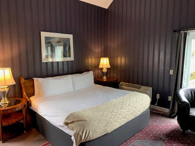 Cozy bedroom featuring a large bed, two bedside lamps, and a view of a window.