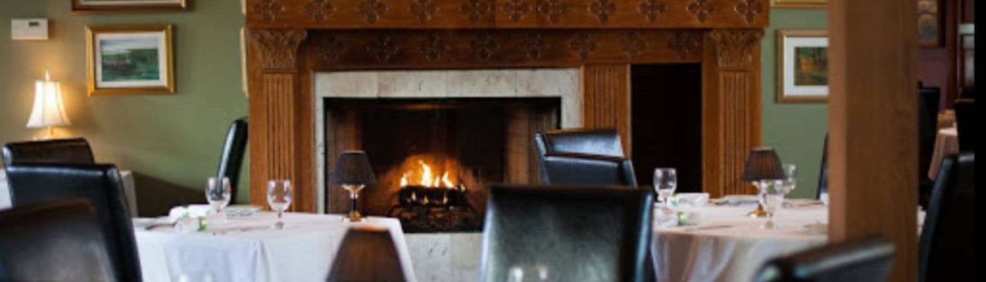 A cozy restaurant interior featuring a fireplace and elegantly set tables.