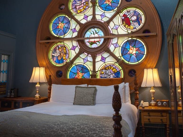 A bed woth a large stained glass behind it