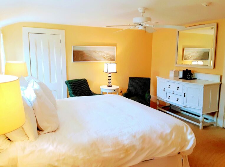 Photo of a guest room with yellow walls and a white bed