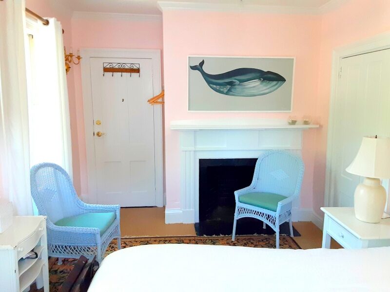 A pink guest room shows a fireplace with a whale painting over it