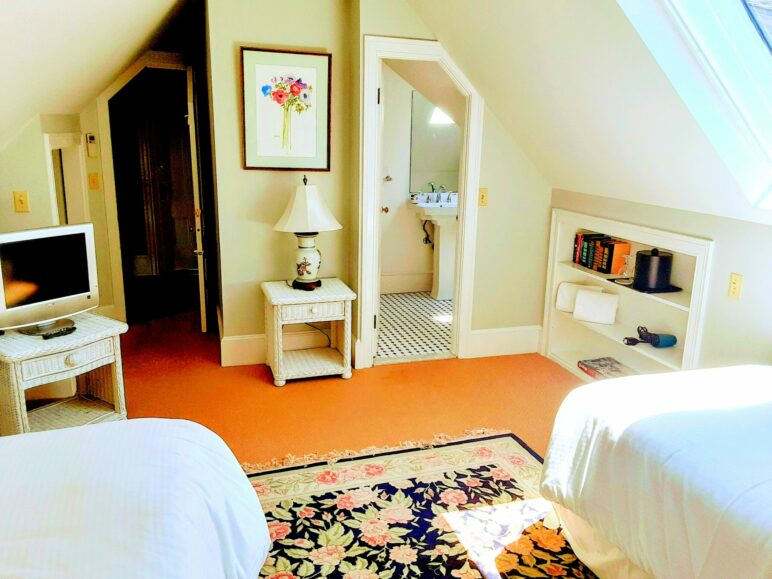 2 twin beds face a bathroom with an oriental rug in between