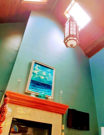 A church lantern hangs over a fireplace in a high ceiling room