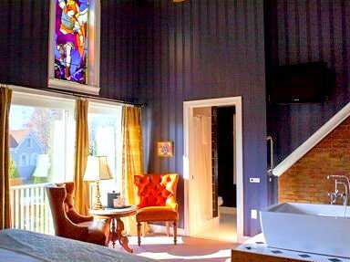 A blue colored guest room has a brightly colored stained glass mural
