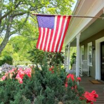 An American flag flies over an old front porch